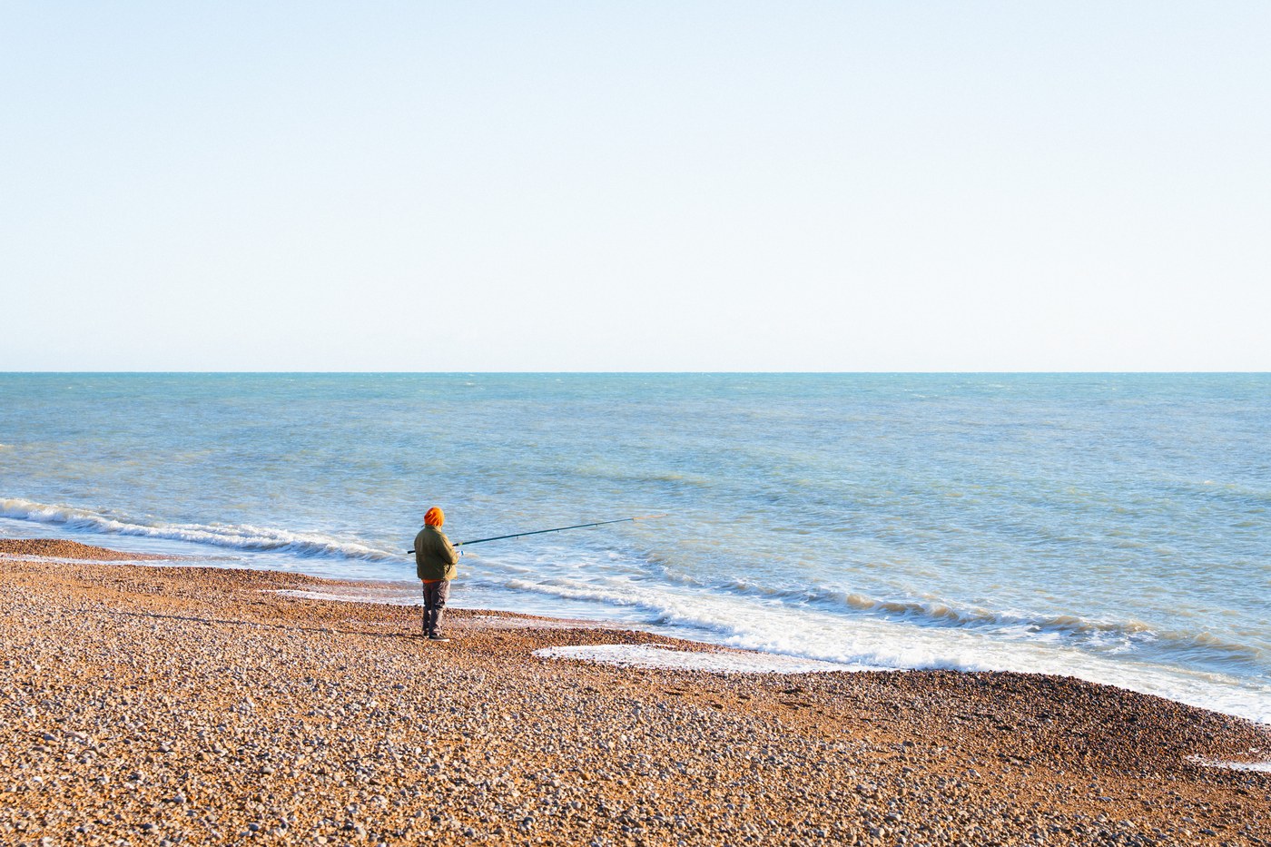 A lone fisherman on the shingle beach at Hastings, looking out to sea