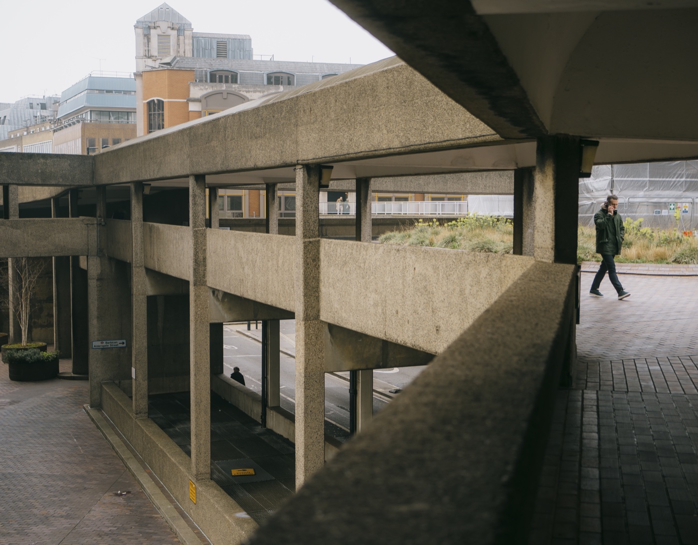 A single figure on the upper walkway of the Barbican Estate, the geometry stripped to monochrome